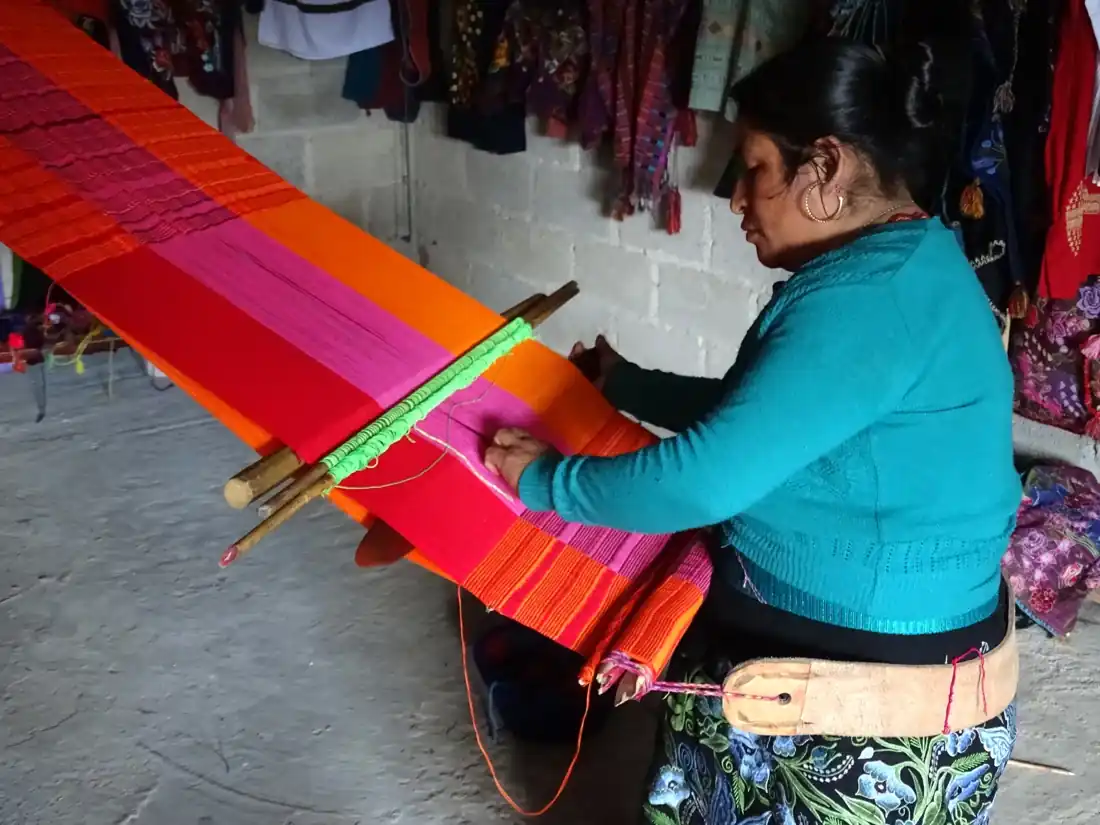 Artesana de Chiapas trabajando en un telar con textiles de colores